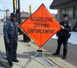 Coatesville Police Officer Sylvester Earle (left) and Cpl. Jonathan Shave display a sign reminding drivers that aggressive driving will produce negative consequences.
