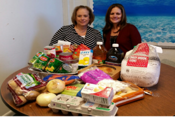 Mrs. Hackmeister and Mrs. Knecht seated in front of donated items for one family”